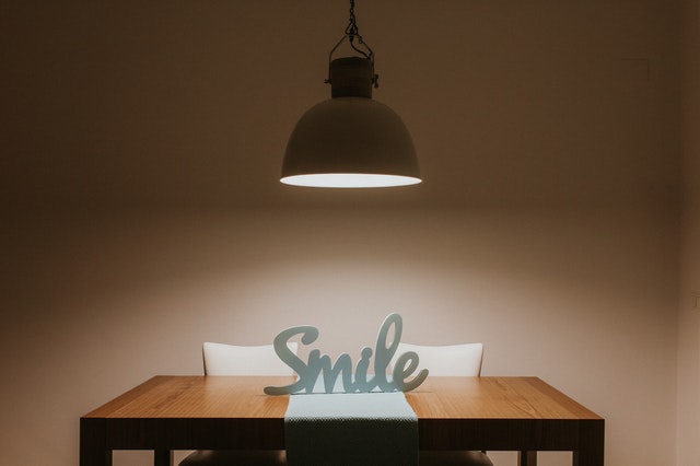Lampa nad stolom, kde je položený nápis Smile 